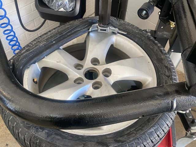 A mechanic checking tire tread depth and tire pressure with a gauge