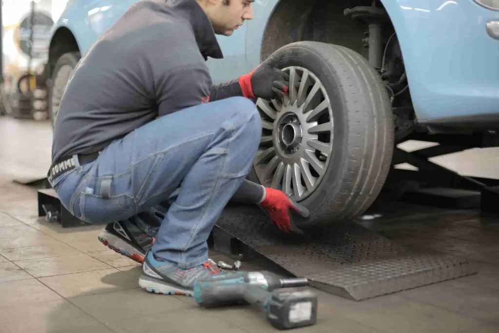 A mechanic rotating tires on a car lift