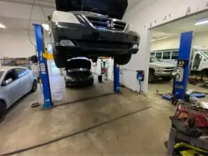 Inside view of busy automotive workshop with 4 bays occupied by various vehicles and hydraulic lifts on display