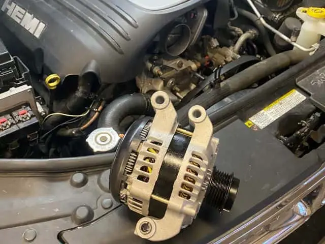 A mechanic replacing the alternator on a car engine