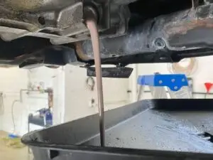 Imagen de un mecánico realizando servicio de mantenimiento a la transmisión de un vehículo, destacando la importancia de mantener en buen estado la transmisión para garantizar el buen funcionamiento del vehículo.