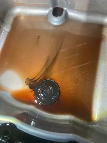 The image shows the fluid pan of a 6L80 automatic transmission. The pan is a flat, rectangular piece of metal located at the bottom of the transmission. The pan surface has various channels and sections, designed to collect and distribute transmission fluid throughout the transmission. There are also a series of magnets embedded in the pan, designed to capture and retain metal particles and other debris in the transmission fluid, helping to keep the fluid clean and extend transmission life. In the image, the fluid tray can be viewed from a lower angle, allowing one to see the shape and arrangement of the channels and sections on its surface. You can also clearly see the magnets embedded in the tray. The image shows the importance of the fluid pan as a critical automatic transmission component, and how its design is optimized to keep transmission fluid clean and provide proper lubrication for transmission components.